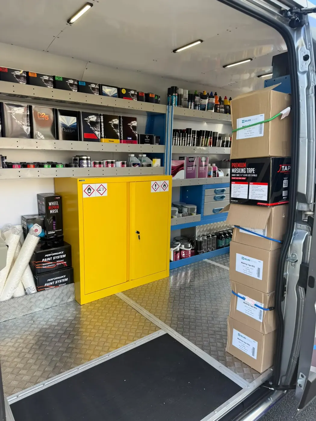 Van side storage with blue shelving units and a yellow safety cabinet